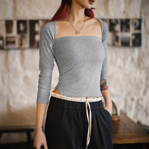 Person wearing a gray long-sleeve top and black pants in an indoor setting